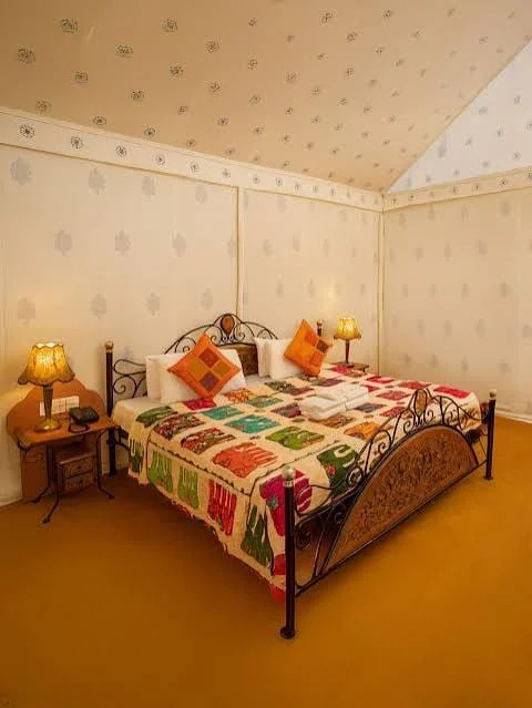Inside a tent: double bed, bedside lamps, block-print quilt